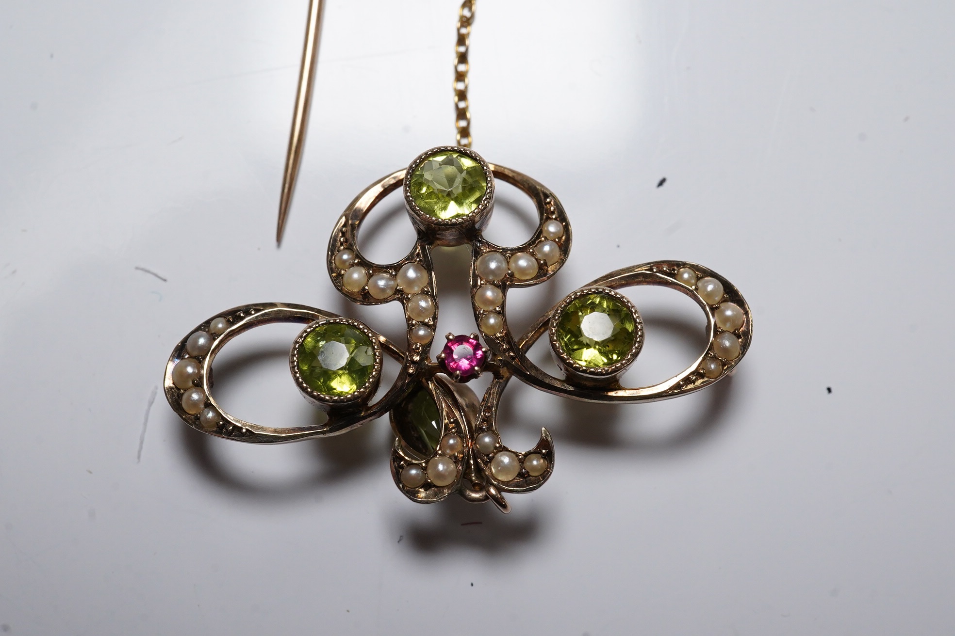 An early 20th century yellow metal, peridot, seed pearl and ruby cluster set drop pendant brooch (pin broken), width 35mm, gross weight 3.6 grams. Condition - poor